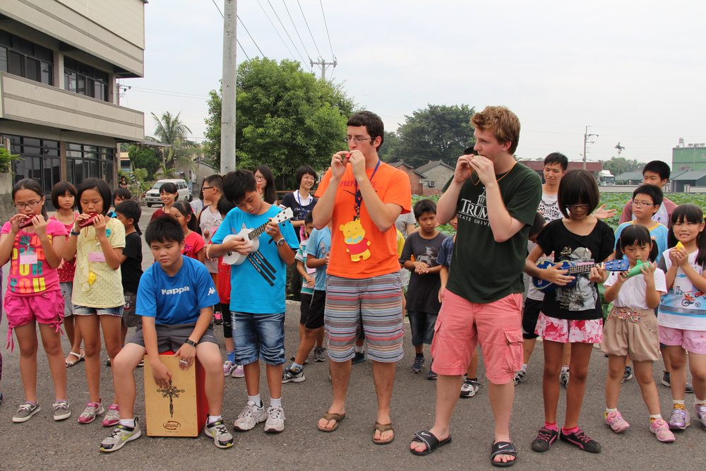 Visiting teachers and Taiwanese students playing ocarinas together outdoors